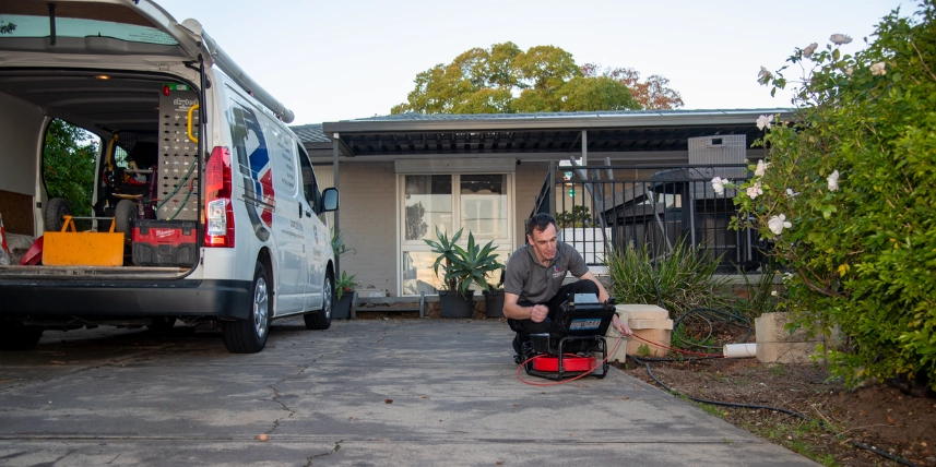 Ashley Townend setting up CCTV drain inspection equipment at a client's home.